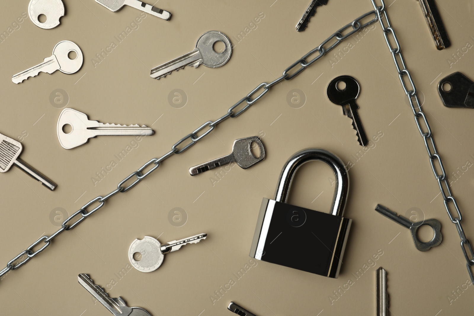 Photo of Steel padlock, keys and chains on beige background, flat lay. Safety concept