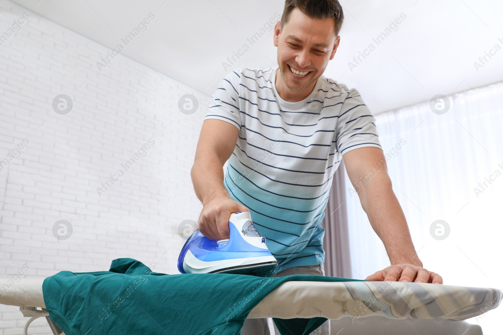 Photo of Man ironing clothes on board at home