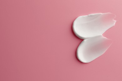 Photo of Sample facial cream on pink background, top view. Space for text