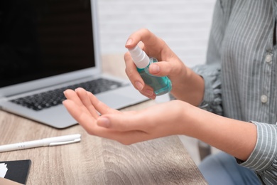 Photo of Office employee applying hand sanitizer at workplace, closeup