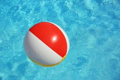 Photo of Colorful beach ball floating in swimming pool on sunny day. Space for text