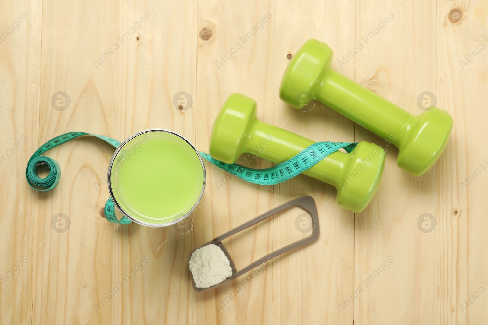 Photo of Tasty shake, dumbbells, measuring tape and powder on wooden table, flat lay. Weight loss