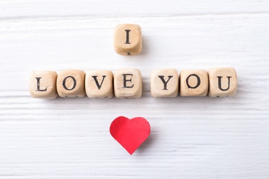 Cubes with words I Love You and paper heart on white wooden background, flat lay