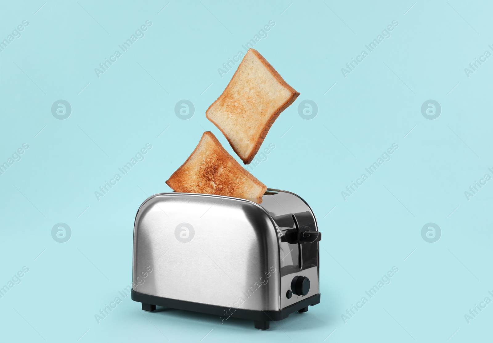 Photo of Bread slices popping up from modern toaster on light blue background