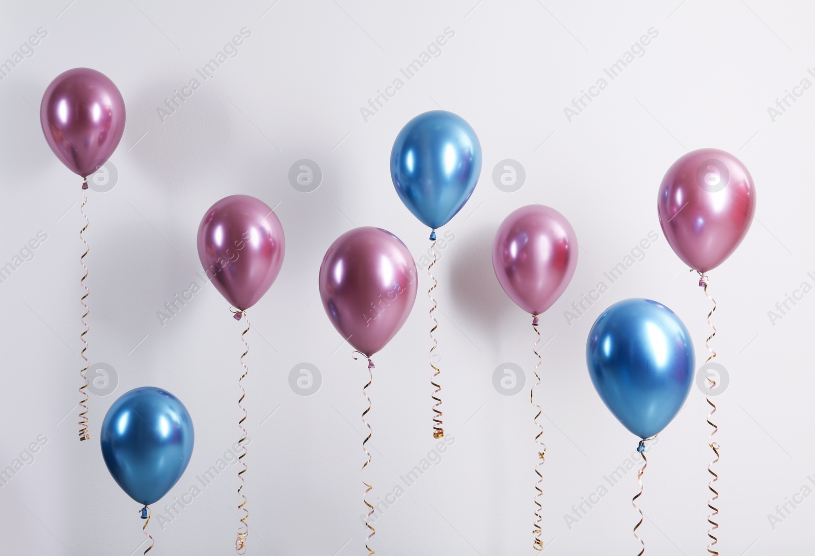 Photo of Color balloons with ribbons on white background