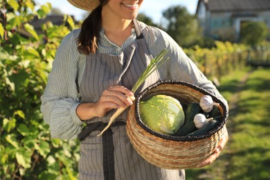 Photo of Woman with basket of different fresh ripe vegetables on farm, closeup