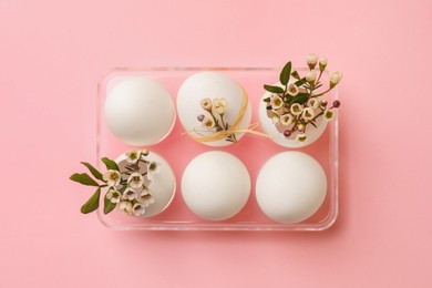 Photo of Festive composition with eggs and floral decor on pink background, top view. Happy Easter