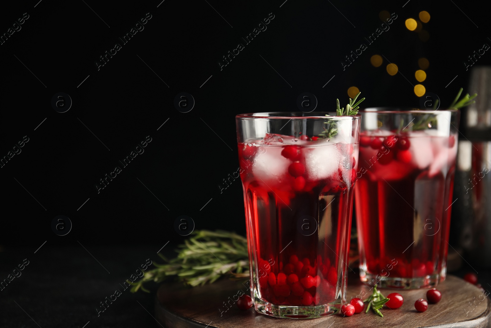 Photo of Tasty refreshing cranberry cocktail with rosemary on black table. Space for text