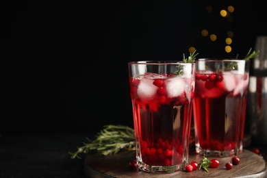 Photo of Tasty refreshing cranberry cocktail with rosemary on black table. Space for text