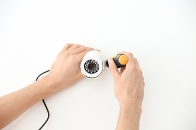 Technician installing CCTV camera on wall indoors, closeup