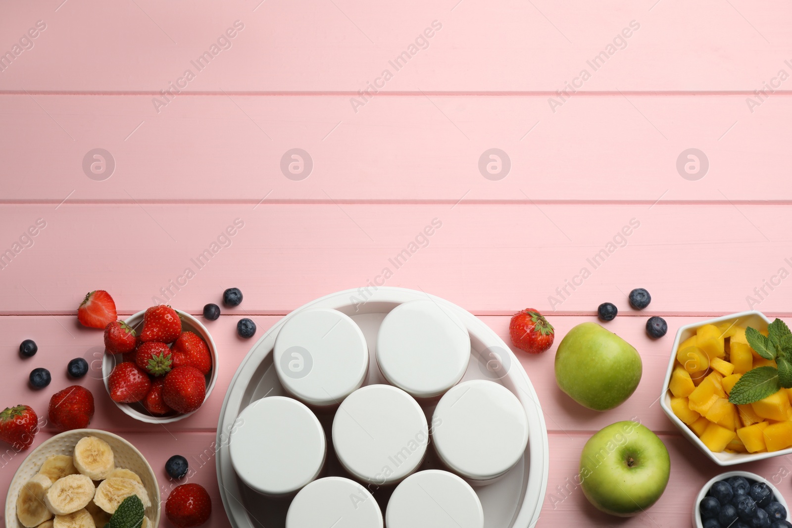 Photo of Modern yogurt maker with full jars and different fruits on pink wooden table, flat lay. Space for text