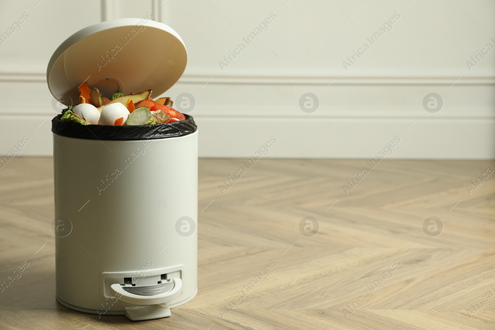 Photo of Trash bin with natural garbage on wooden background, space for text. Composting of organic waste