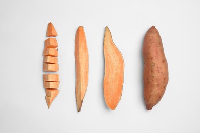 Cut and whole sweet potatoes on white background, top view