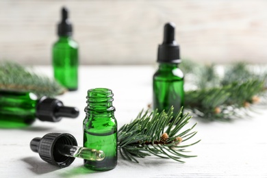 Composition with bottle of conifer essential oil on white wooden table. Space for text