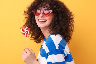 Photo of Beautiful woman in sunglasses with lollipop on yellow background