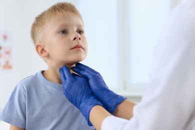 Endocrinologist examining boy's thyroid gland at hospital, closeup