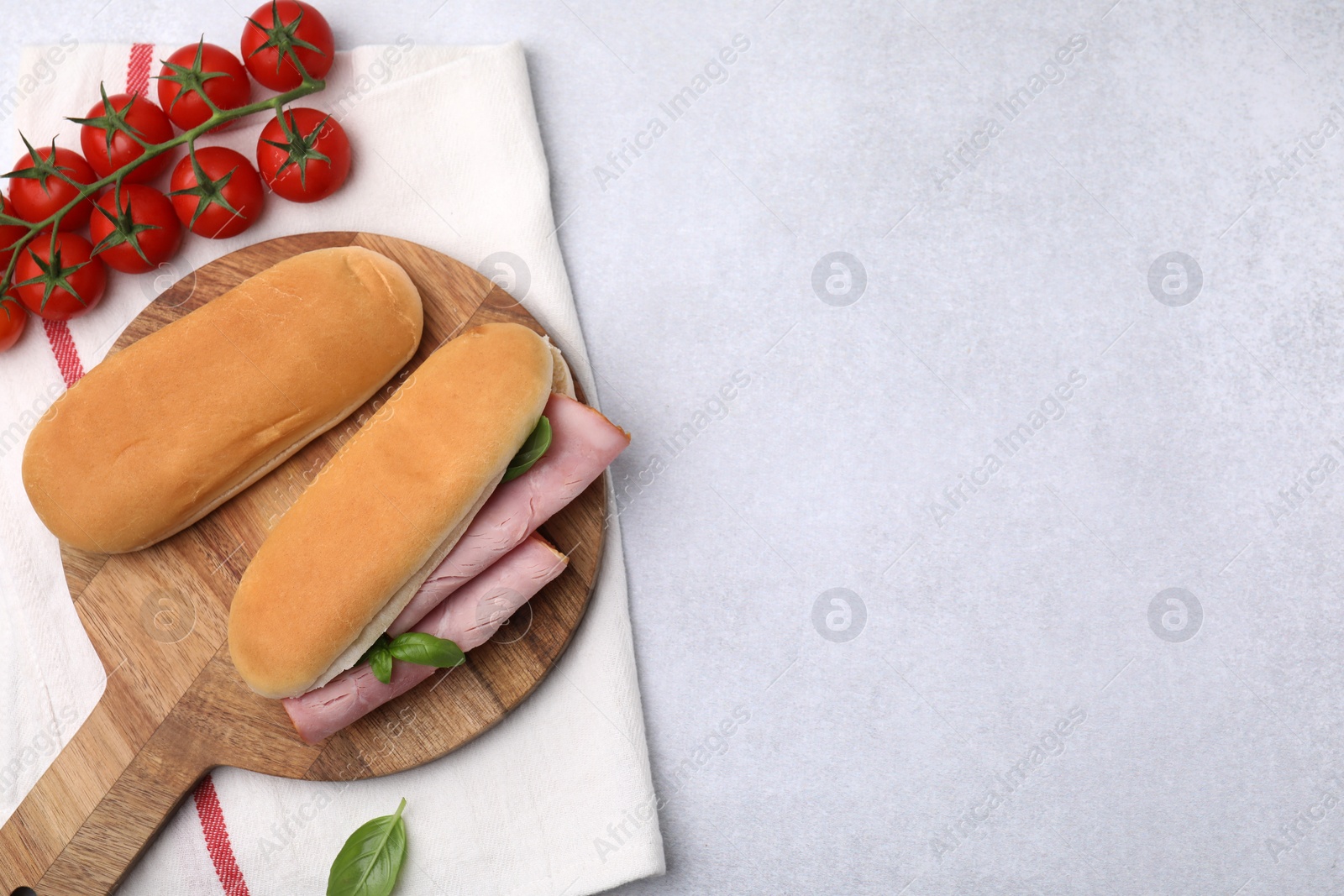 Photo of Delicious sandwich with ham, basil and products on light grey table, flat lay. Space for text