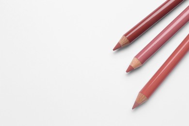 Different lip pencils on white background, top view. Cosmetic product