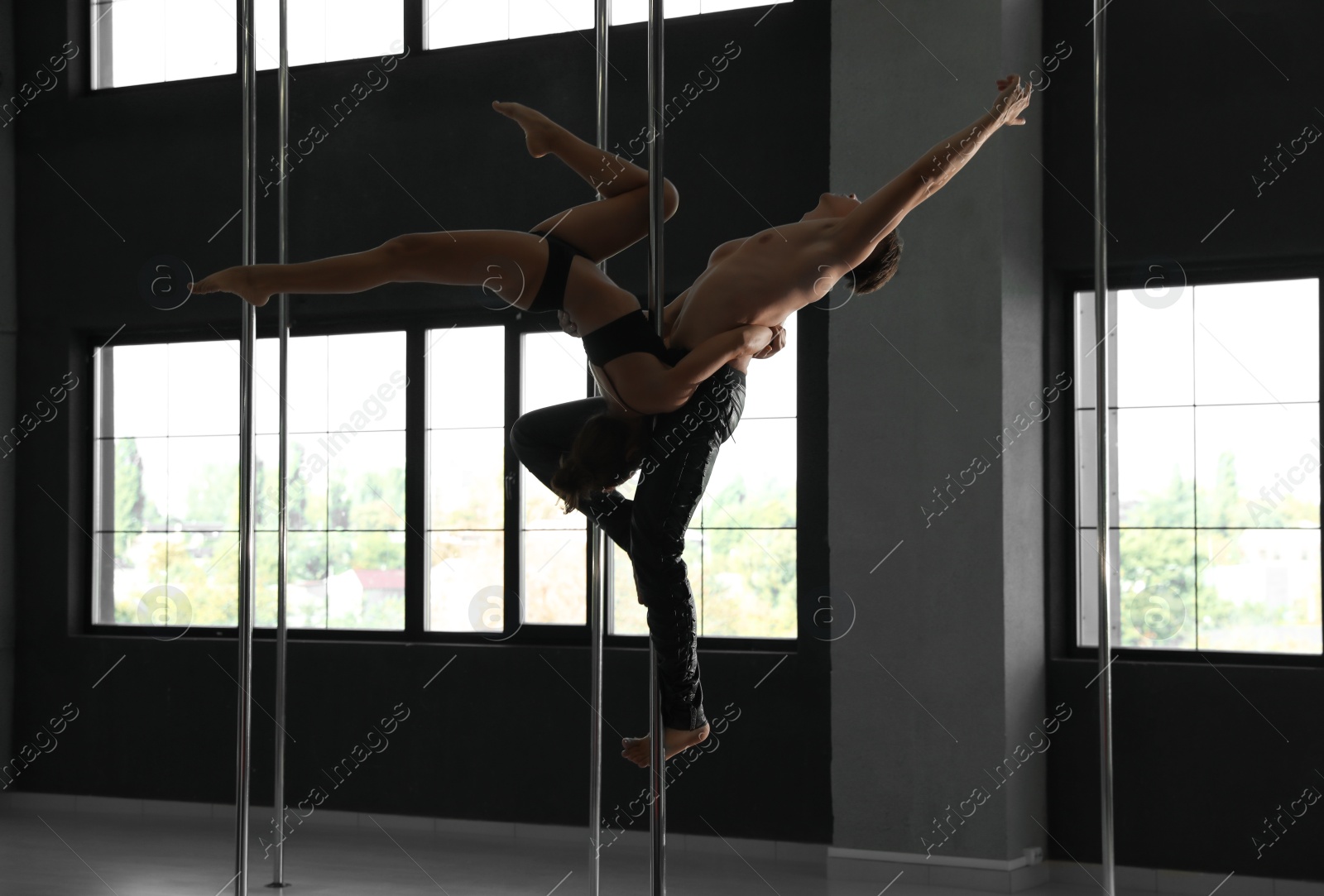 Photo of Young couple dancing in studio with poles