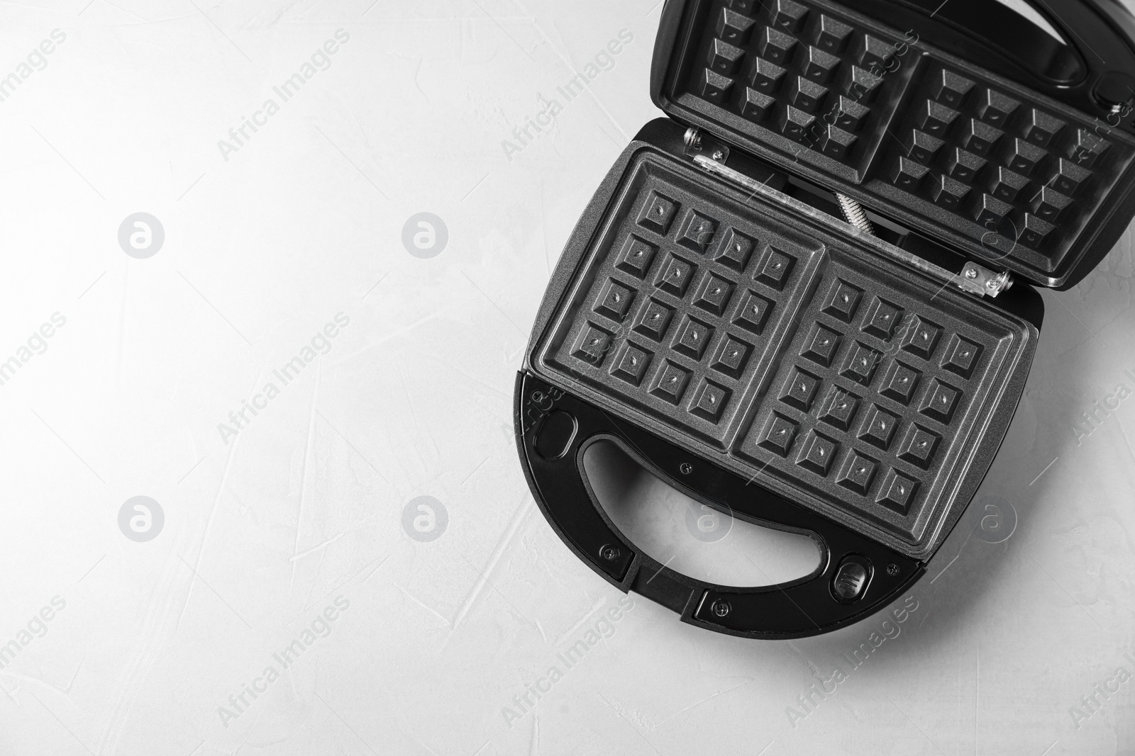 Photo of Modern waffle iron on white table, top view. Space for text