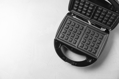 Photo of Modern waffle iron on white table, top view. Space for text