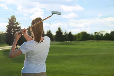 Photo of Woman playing golf on green course, back view. Space for text