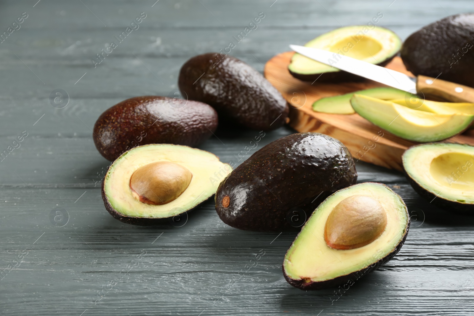 Photo of Whole and cut avocados on grey wooden table