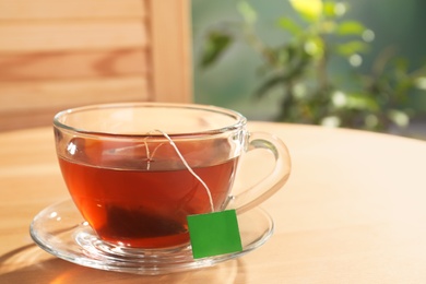 Photo of Brewing tea with bag in cup on table. Space for text