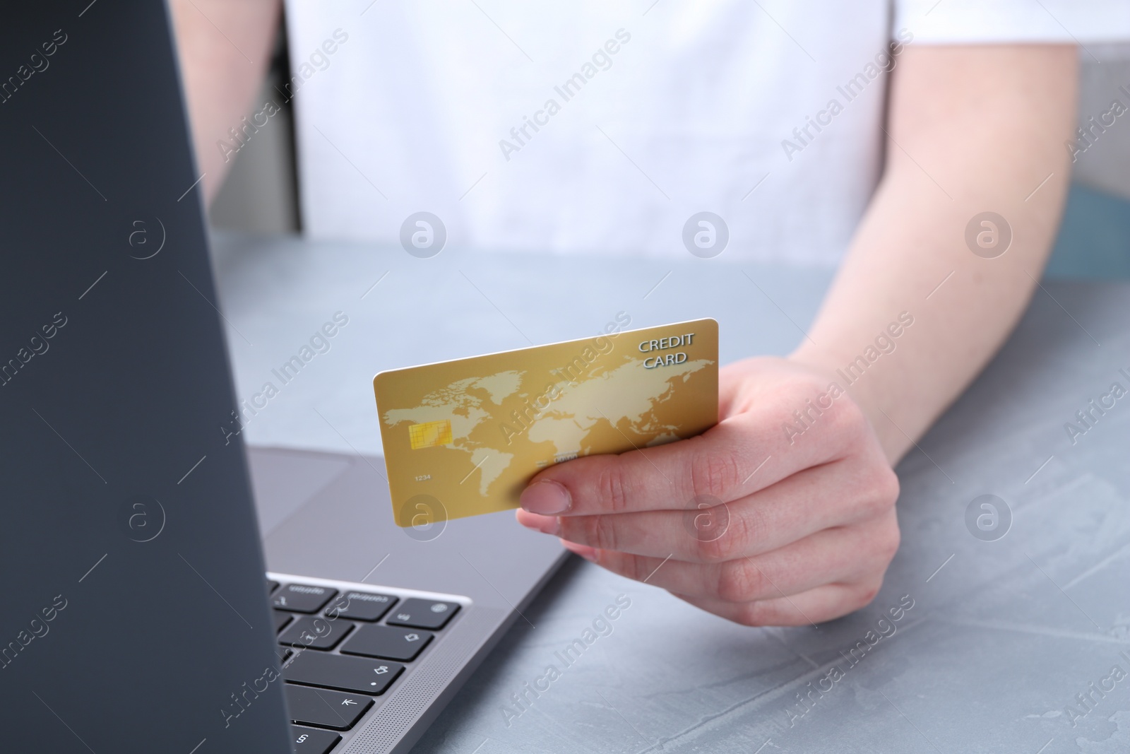 Photo of Online payment. Woman with laptop and credit card at white table, closeup