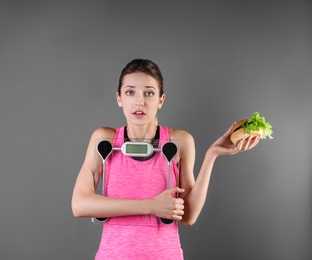 Photo of Young beautiful woman with scales and sandwich on color background. Weight loss motivation