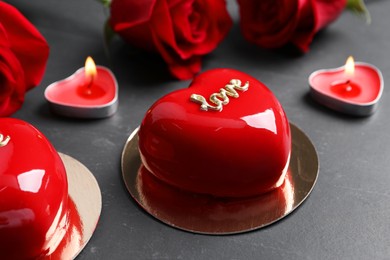 Photo of St. Valentine's Day. Delicious heart shaped cakes, roses and candles on black table, closeup