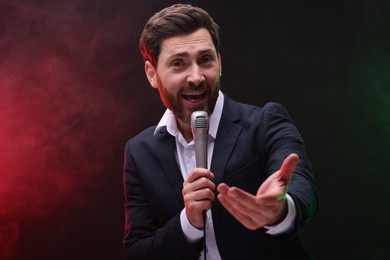 Emotional man with microphone singing in color light