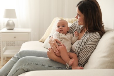 Photo of Young woman with her little baby on sofa at home