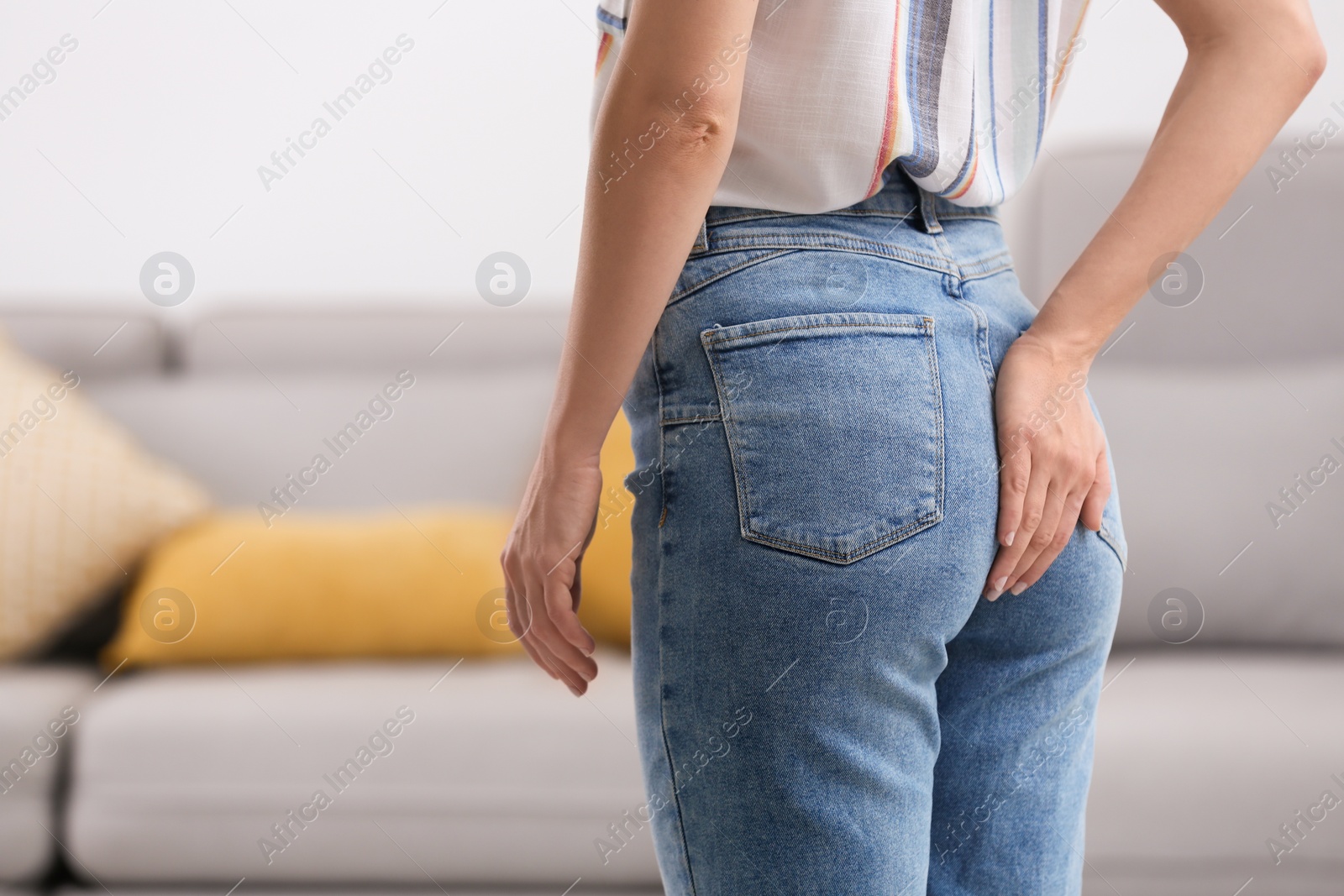 Photo of Young woman suffering from hemorrhoid at home, closeup