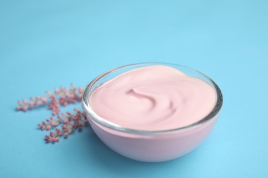 Photo of Professional face mask with flowers on light blue background, closeup