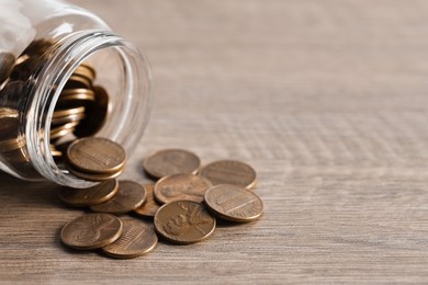 Glass jar with coins on wooden table. Space for text