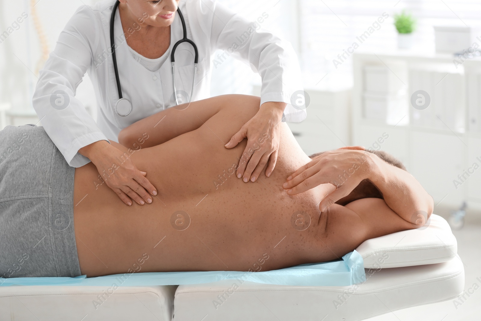 Photo of Female orthopedist examining patient's back in clinic, closeup