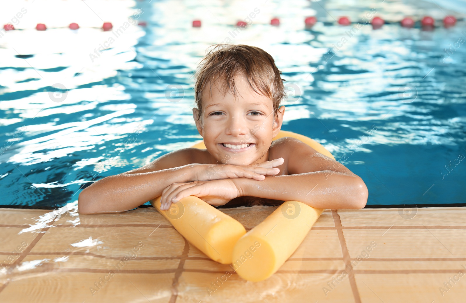 Photo of Little boy with swimming noodle in indoor pool