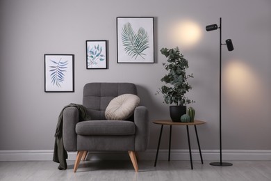 Photo of Stylish room interior with comfortable armchair and green eucalyptus tree