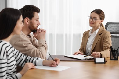 Couple signing document while having meeting with lawyer in office, selective focus