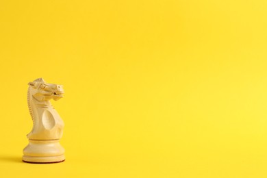 Photo of Wooden knight on yellow background, space for text. Chess piece
