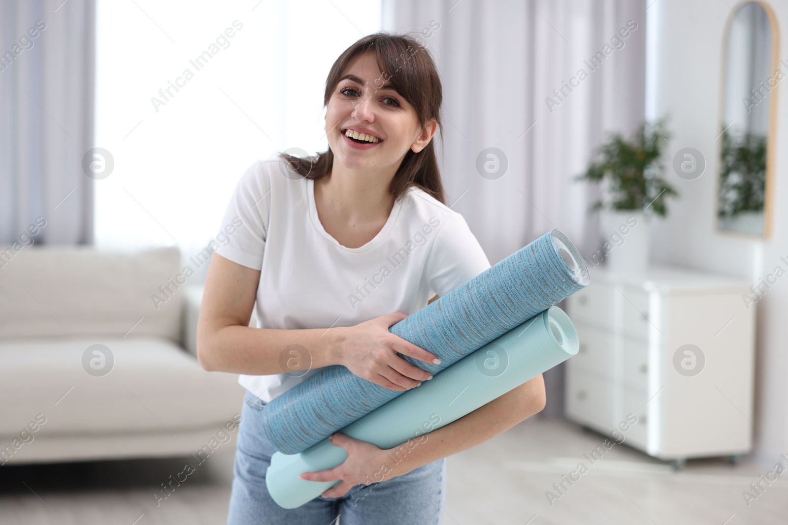 Photo of Woman with light blue wallpaper rolls in room