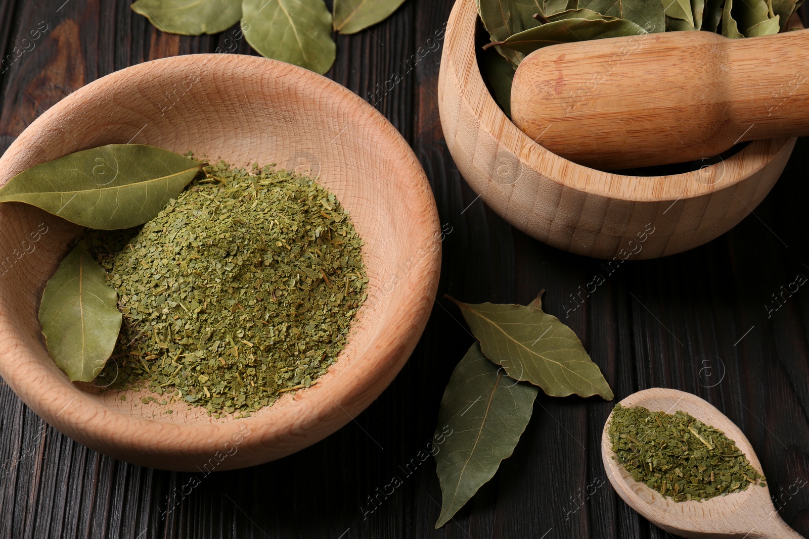 Photo of Whole and ground aromatic bay leaves on wooden table