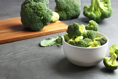 Photo of Bowl of fresh broccoli on grey table. Space for text