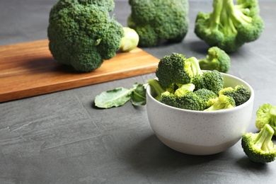 Bowl of fresh broccoli on grey table. Space for text