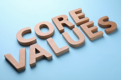 Photo of Phrase CORE VALUES made of wooden letters on light blue background