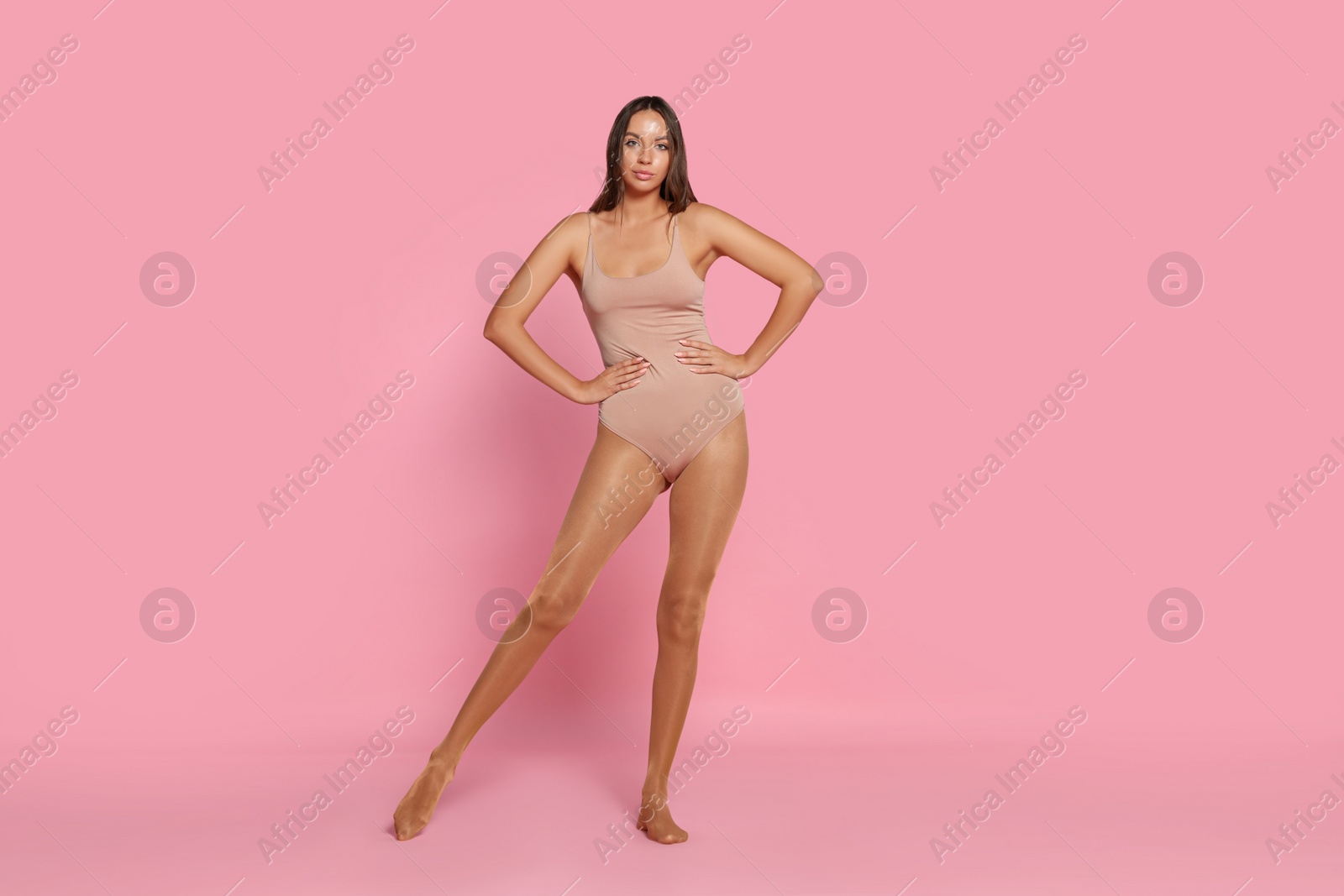 Photo of Beautiful woman wearing tights and bodysuit on pink background