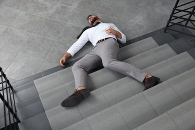 Photo of Unconscious man lying on floor after falling down stairs indoors
