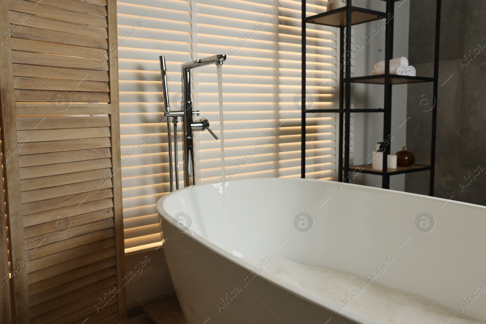 Photo of Stylish bathroom interior with modern white tub and shelving unit