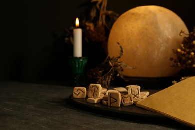 Composition with wooden runes and old book on black table